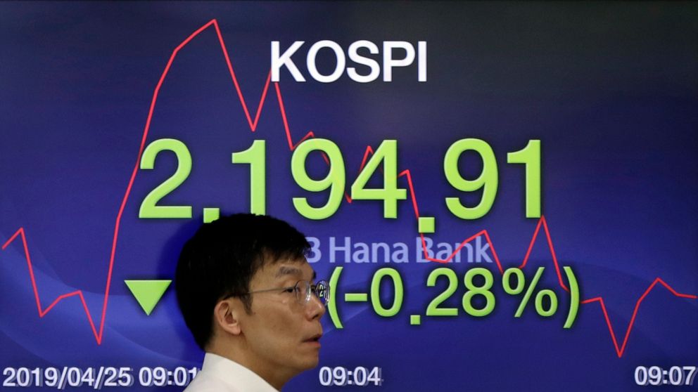 A currency trader walks by the screen showing the Korea Composite Stock Price Index (KOSPI) at the foreign exchange dealing room in Seoul, South Korea, Thursday, April 25, 2019. Asian shares were mixed Thursday after U.S. stocks closed lower, giving 