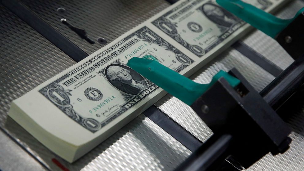FILE - New $1 bills with the signatures of U.S. Treasurer Jovita Carranza and Treasury Secretary Steven Mnuchin are cut and stacked at the Bureau of Engraving and Printing in Washington, Nov. 15, 2017. More workers are following experts' advice in sa