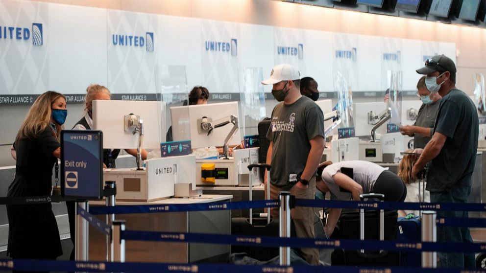FILE - Travelers well up as agents confer at the United Airlines ticketing counter in Denver International Airport Friday, July 2, 2021, in Denver. United Airlines reported a $473 million profit for the third quarter thanks to more than $1 billion in