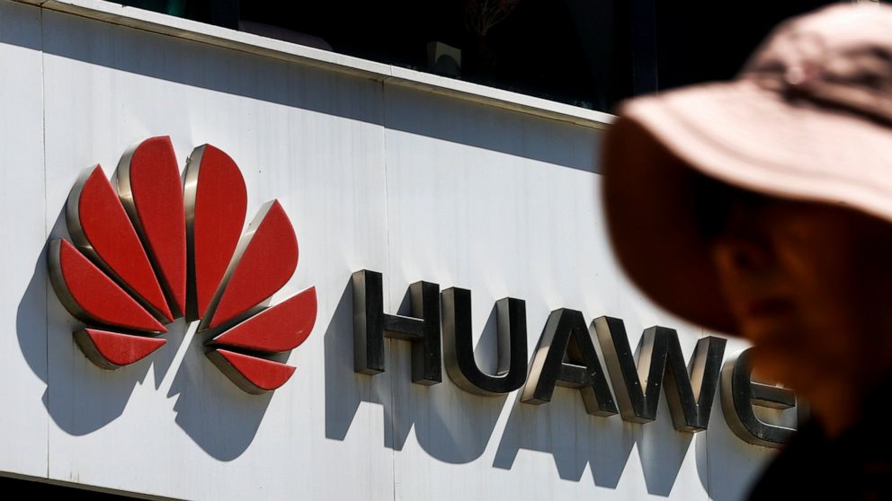 FILE - In this May 29, 2019, file photo, a woman walks by a Huawei retail store in Beijing. The world's largest association of technology professionals has reversed a decision that would have excluded employees of Chinese tech giant Huawei and its af