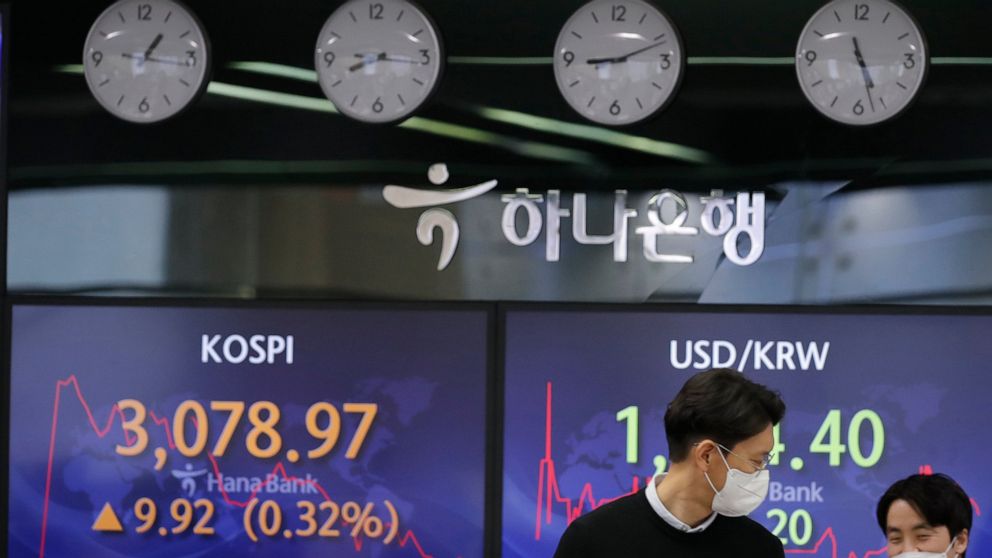 Currency traders walk by the screens showing the Korea Composite Stock Price Index (KOSPI), left, and the foreign exchange rate between U.S. dollar and South Korean won at the foreign exchange dealing room in Seoul, South Korea, Friday, Jan. 29, 2021