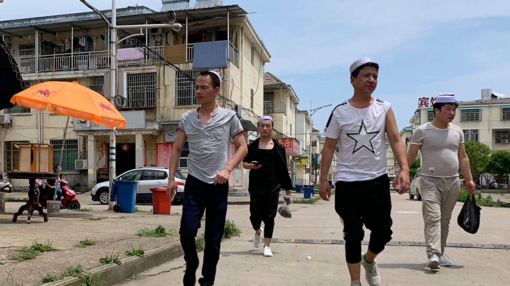 In this June 5, 2019, photo, residents of the Hui Muslim ethnic minority walk in a neighborhood near an OFILM factory in Nanchang in eastern China's Jiangxi province. The Associated Press has found that OFILM, a supplier of major multinational compan