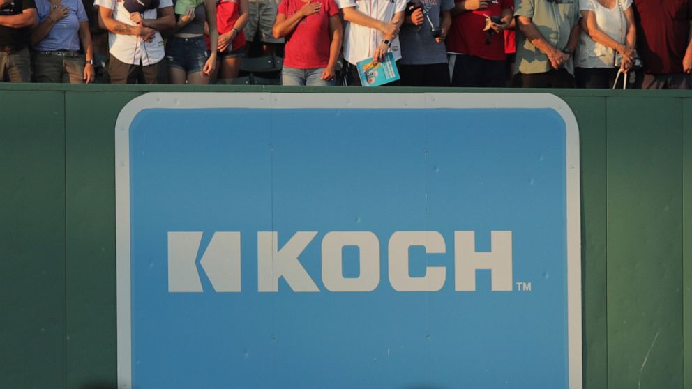 An advertising sign for Koch Industries is shown at Fenway Park in Boston, Tuesday, July 30, 2019. Koch Industries is planning to continue running two glass manufacturing facilities in Russia, saying it doesn’t want to hand over the plants to the Rus