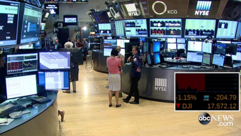 PHOTO: People stand around on the floor of the New York Stock Exchange after trading was halted on July 8, 2015.