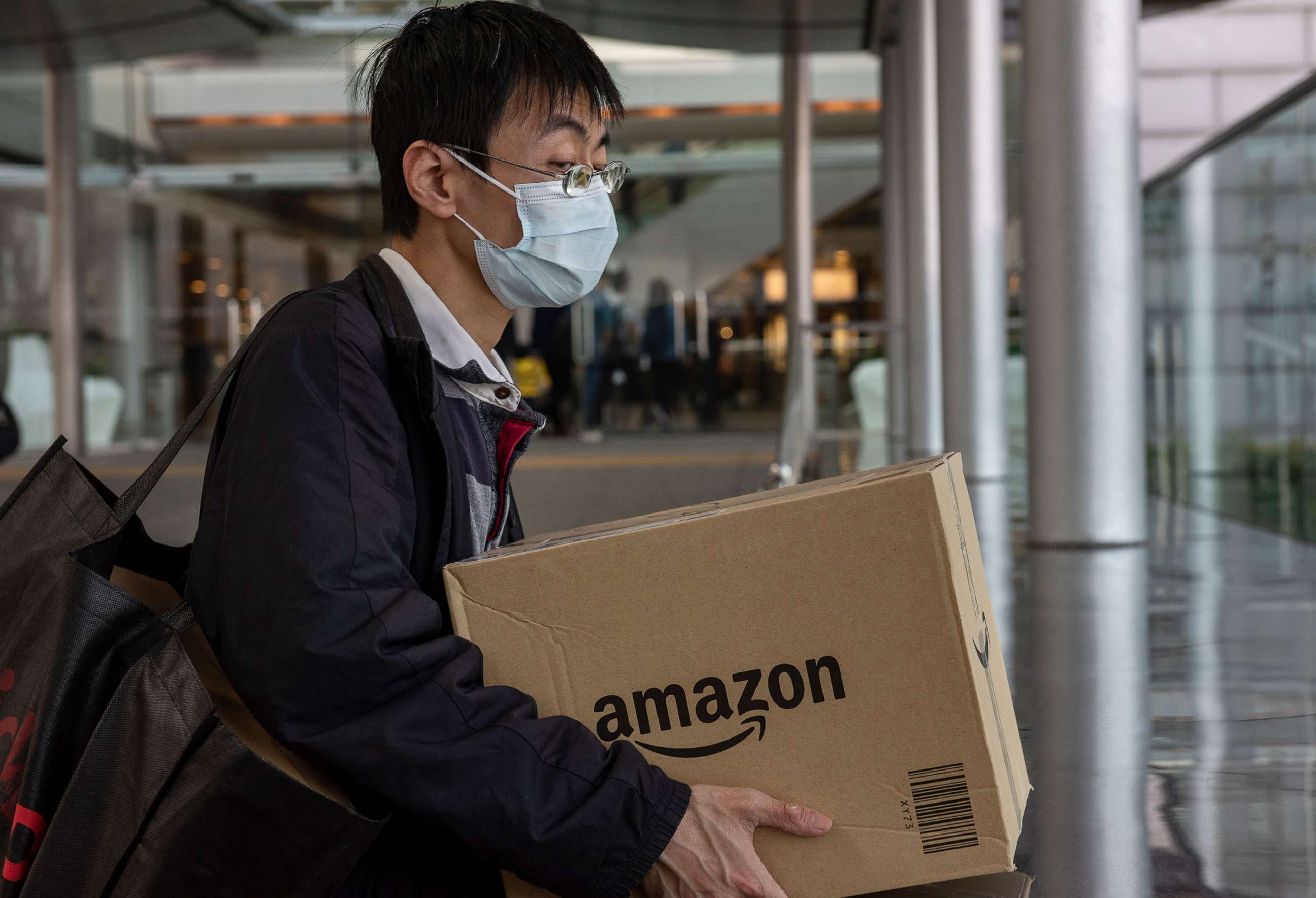 PHOTO: A man wearing a face mask holds a box of the American electronic commerce company Amazon in Central district, Hong Kong, Feb. 12, 2020.
