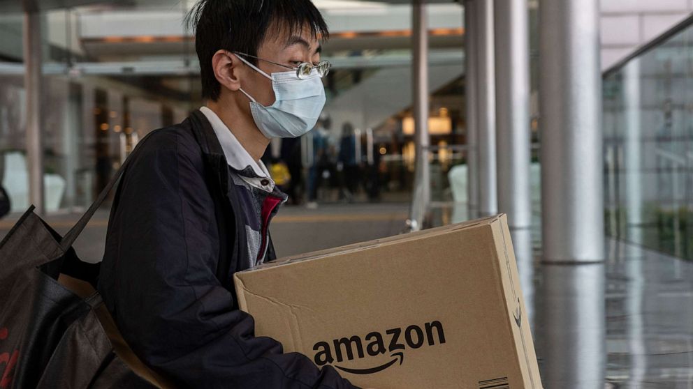 PHOTO: A man wearing a face mask holds a box of the American electronic commerce company Amazon in Central district, Hong Kong, Feb. 12, 2020.
