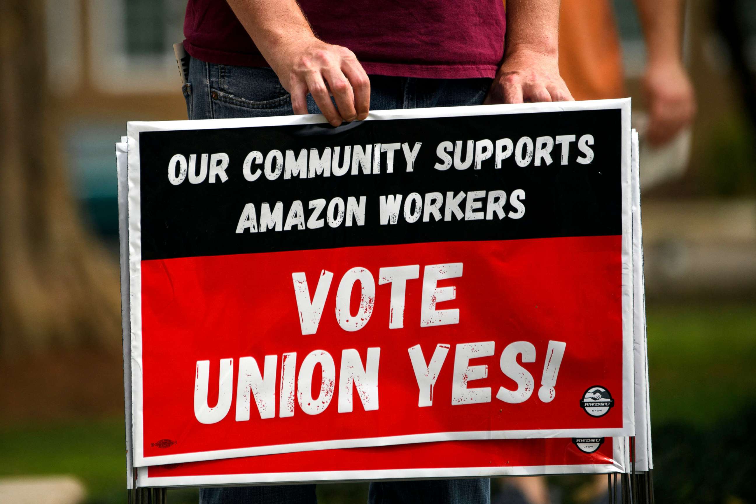 PHOTO: A person holds "Vote Union Yes!" signs during a protest in solidarity with the unionization of Amazon.com fulfillment center workers at Kelly Ingram Park on March 27, 2021 in Birmingham, Ala.