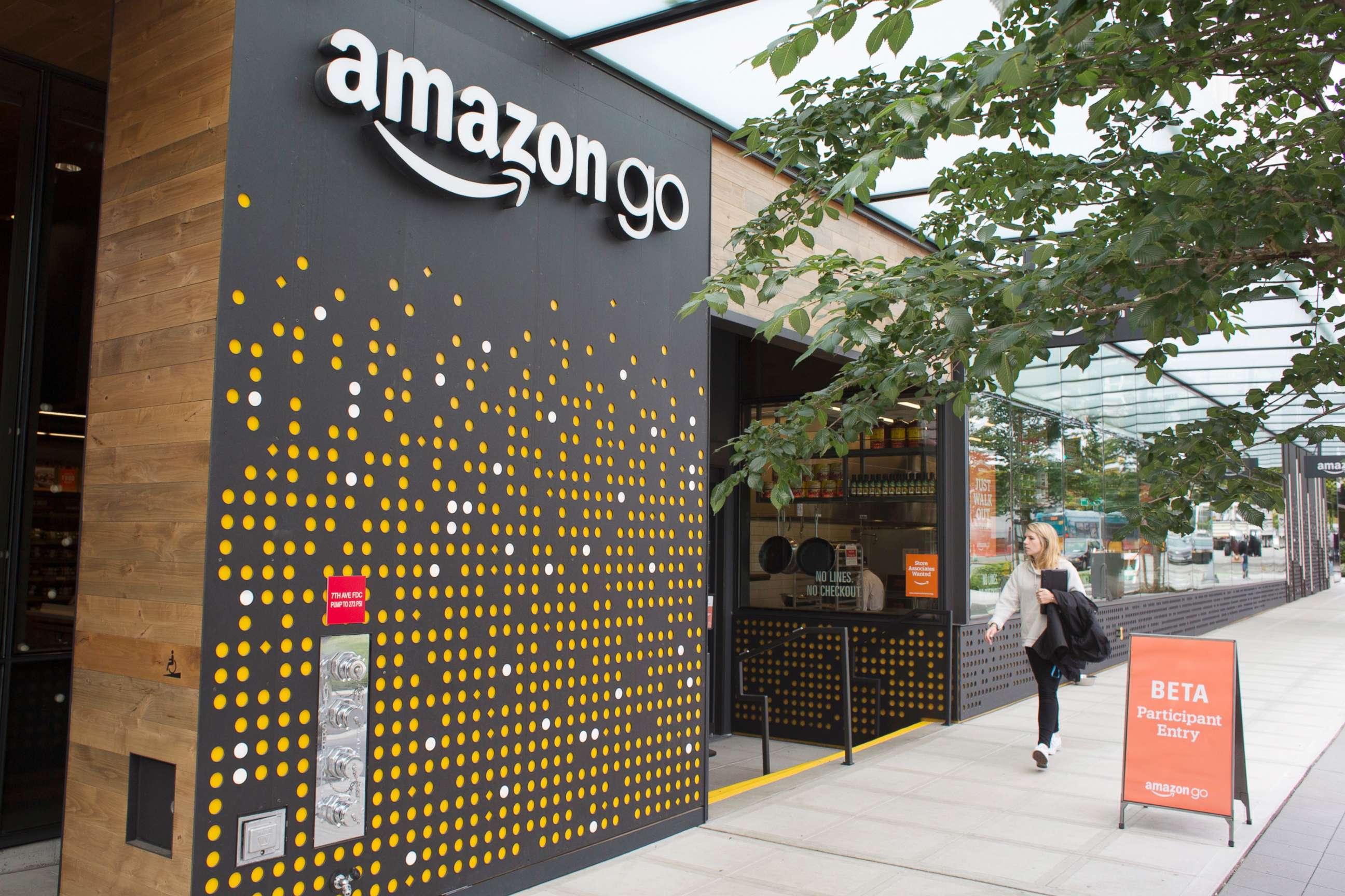 PHOTO: A woman walks past the Amazon Go grocery store at the Amazon corporate headquarters on June 16, 2017, in Seattle.