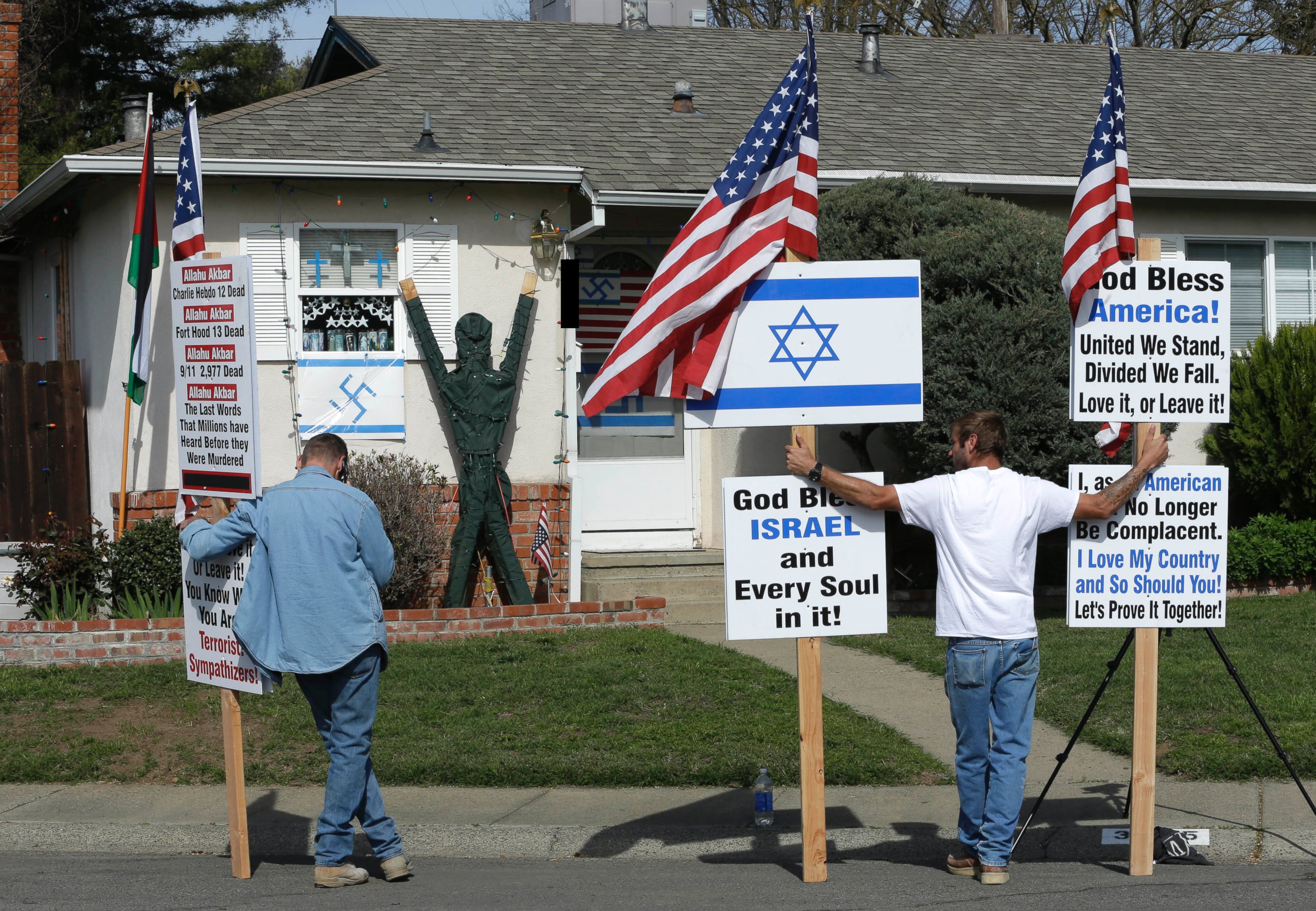 PHOTO: Two men demonstrate outside a home to call for the removal of swastikas displayed on the exterior in Sacramento, Calif., Feb. 26, 2015.