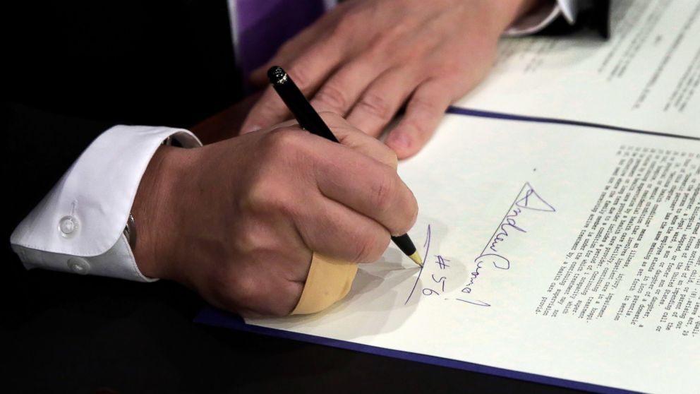 PHOTO: New York Gov. Andrew Cuomo, signs a law that will gradually raise New York's minimum wage to $15, at the Javits Convention Center, in New York, April 4, 2016.
