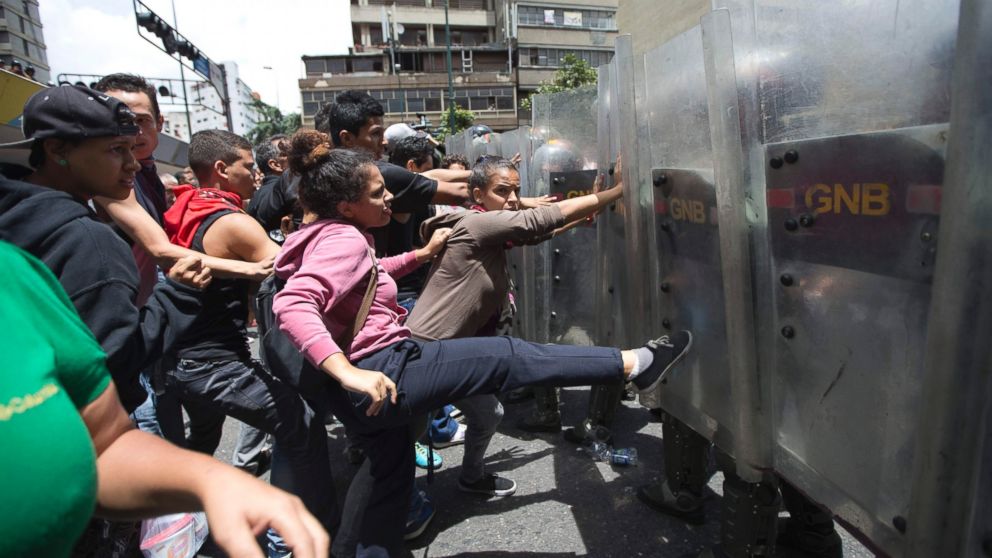 A woman kicks the shield of a National Guard soldier as other demonstrators push during a food protest a few blocks from Miraflores presidential palace in Caracas, Venezuela, June 2, 2016.