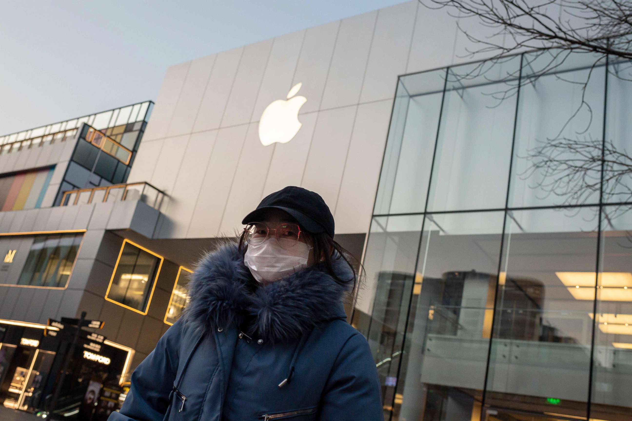 PHOTO: A woman wearing a protective face mask walks outside of a closed-off Apple Store in Beijing, Feb. 3, 2020. 