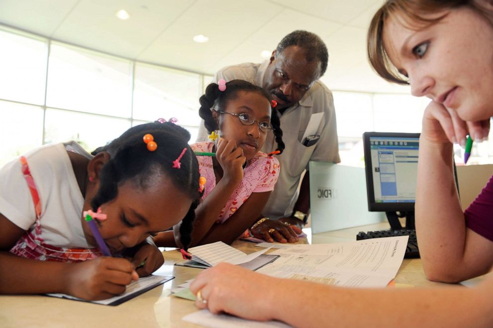 PHOTO: Samuel Spraggins brought his two young granddaughters Tamia Fair, left, 5, and Tamera Fair, 7, to open a savings account in Denver, June 12, 2009.