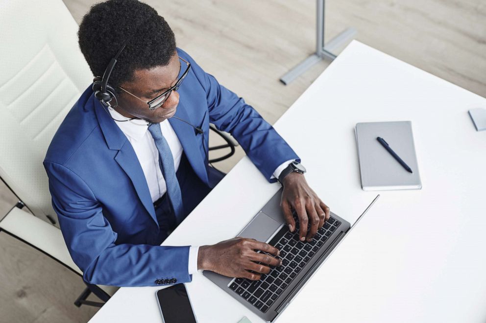 PHOTO: A Black businessman wears headphones while typing on laptop in an undated stock image.