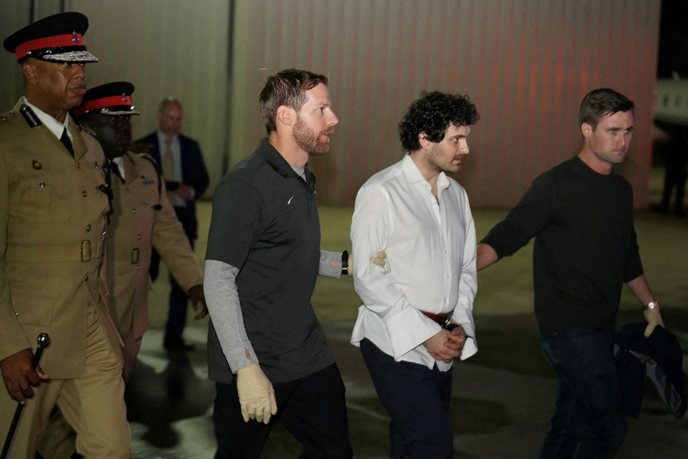 PHOTO: Sam Bankman-Fried, founder and former CEO of crypto currency exchange FTX, is walked in handcuffs to a plane during his extradition to the United States at Lynden Pindling international airport in Nassau, Bahamas, Dec. 21, 2022.