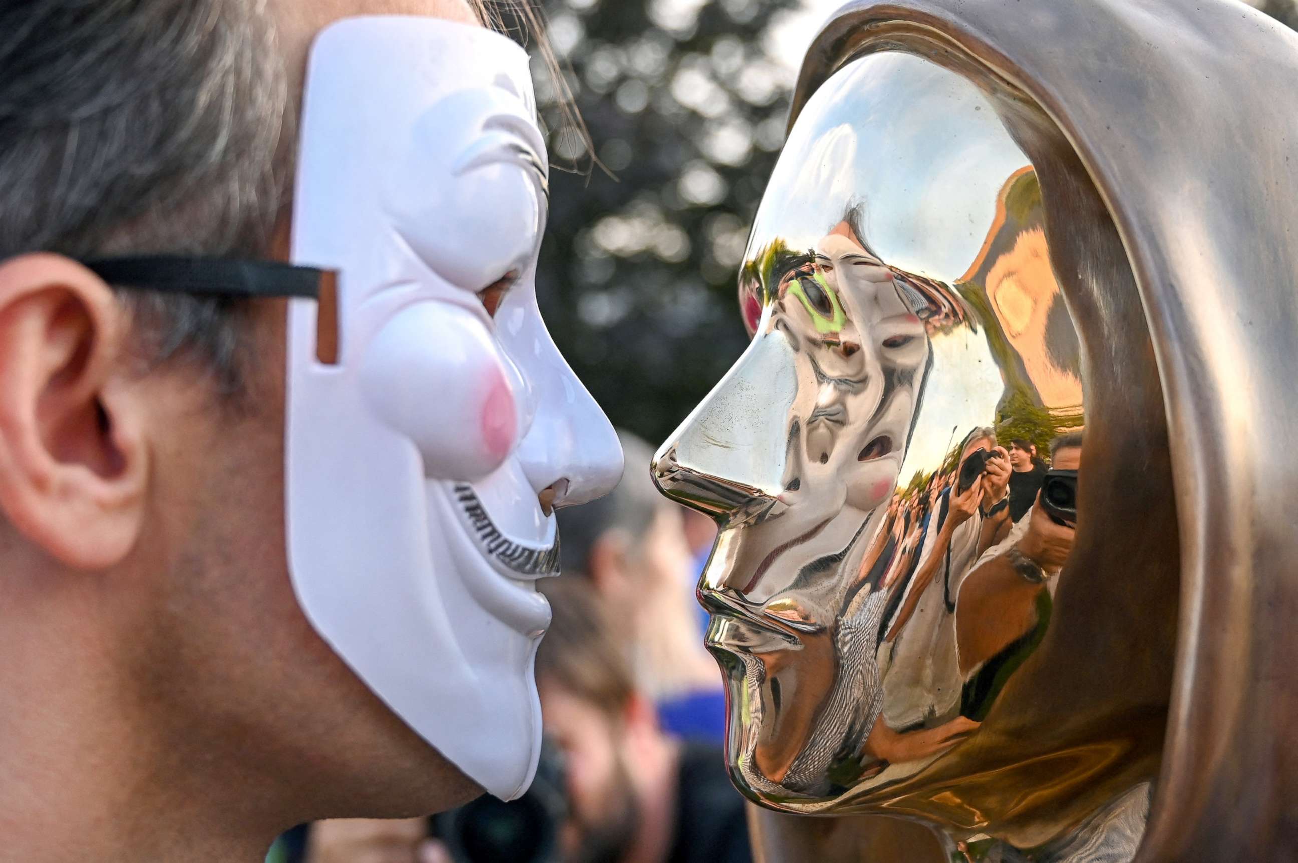 PHOTO: A person wearing a Guy Fawkes mask poses in front of the statue of Satoshi Nakamoto, the mysterious inventor of the virtual currency bitcoin, after its unveiling at the Graphisoft Park in Budapest, Hungary, Sept. 16, 2021.