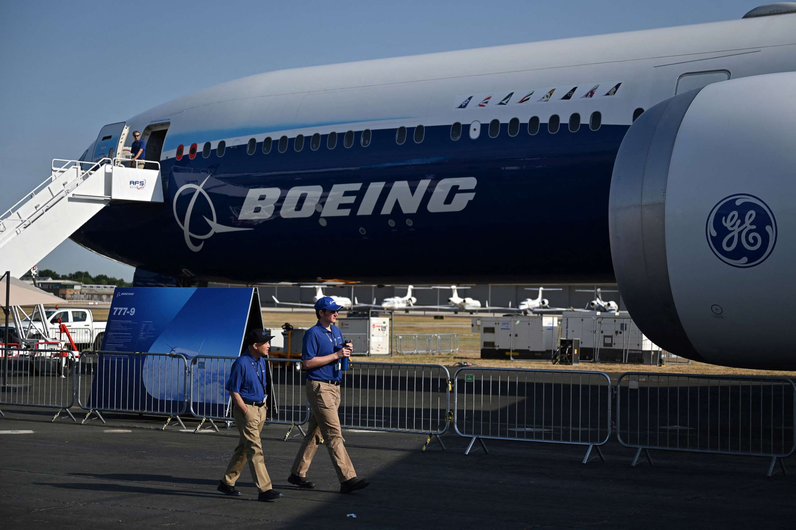 PHOTO: Members of staff walk past a Boeing 777-9 displayed during the Farnborough Airshow, in Farnborough, U.K., July 18, 2022.