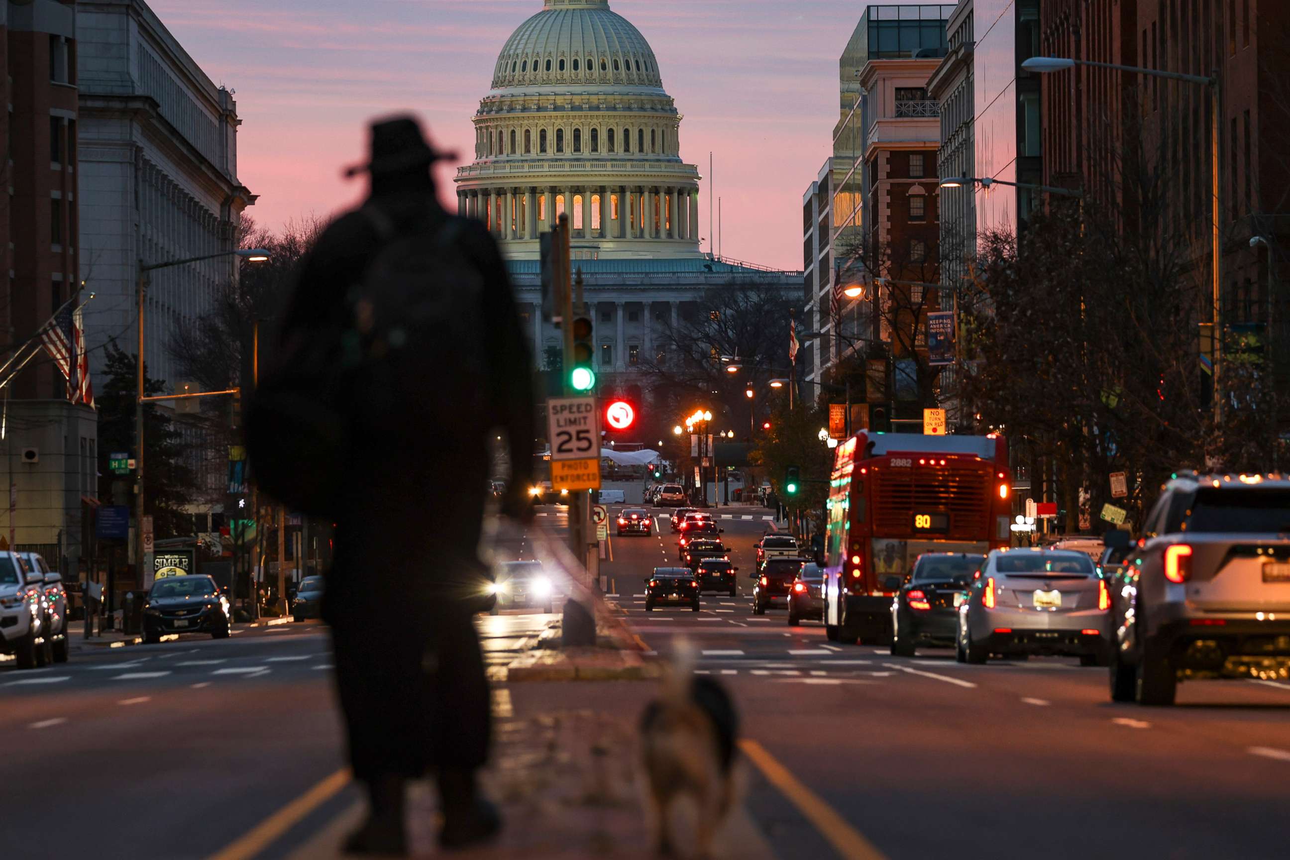 PHOTO: A man walks his dog as the sun rises over the U.S. Capitol, Dec. 28, 2020 in Washington, D.C.