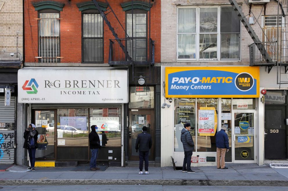 PHOTO: People queue to enter Payomatic, a business that offers check cashing, as unemployment claim figures were released, during the coronavirus disease (COVID-19) outbreak in Manhattan, New York City, April 2, 2020.