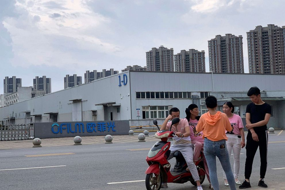 PHOTO: In this June 5, 2019, file photo, people chat near the entrance to an OFILM factory in Nanchang, China. The company is one of 11 that the U.S. government has imposed trade sanctions on and says are implicated in human rights abuses.