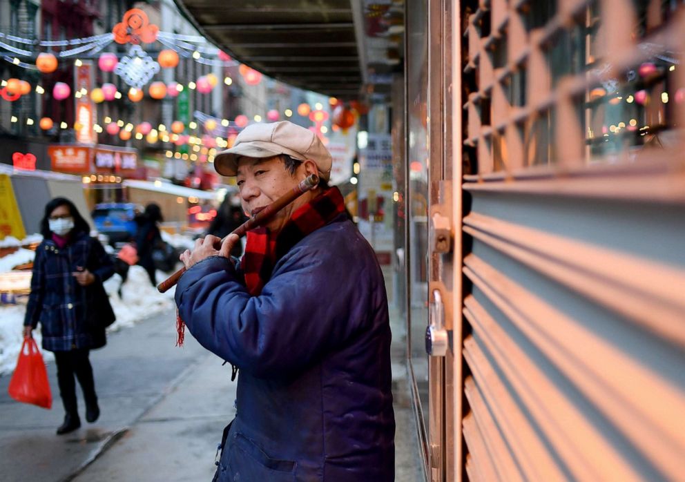 PHOTO: A man plays the flute as people walk through chinatown in New York City, Feb. 11, 2021.