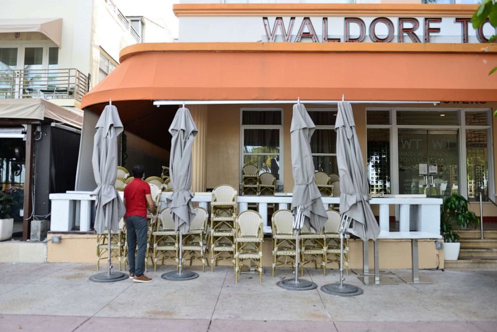 PHOTO: A man is seen stacking up chair of a closed restaurant on Ocean Drive in the entertainment district of Miami Beach on July 20, 2020 in Miami Beach, Florida.