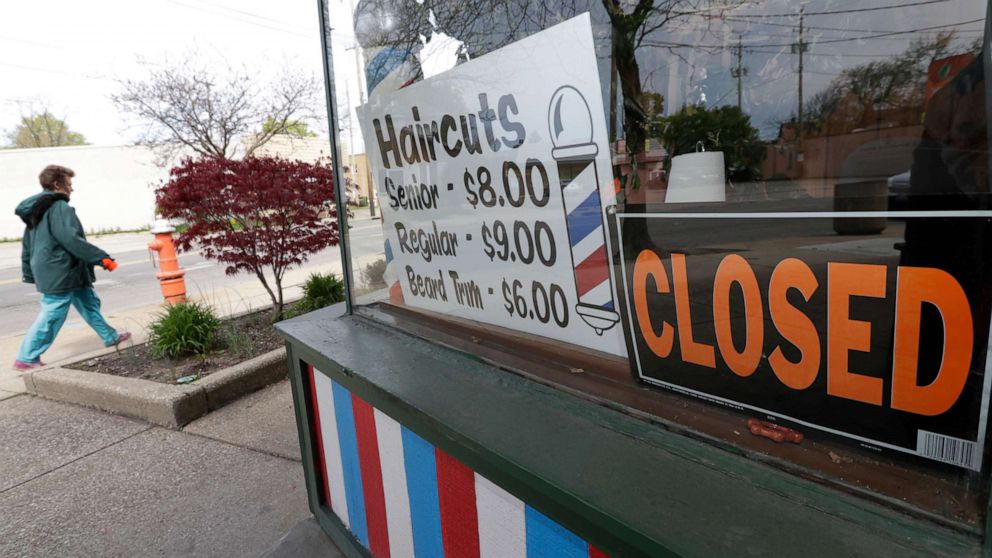 PHOTO: A woman walks past a closed barber shop, May 6, 2020, in Cleveland.
