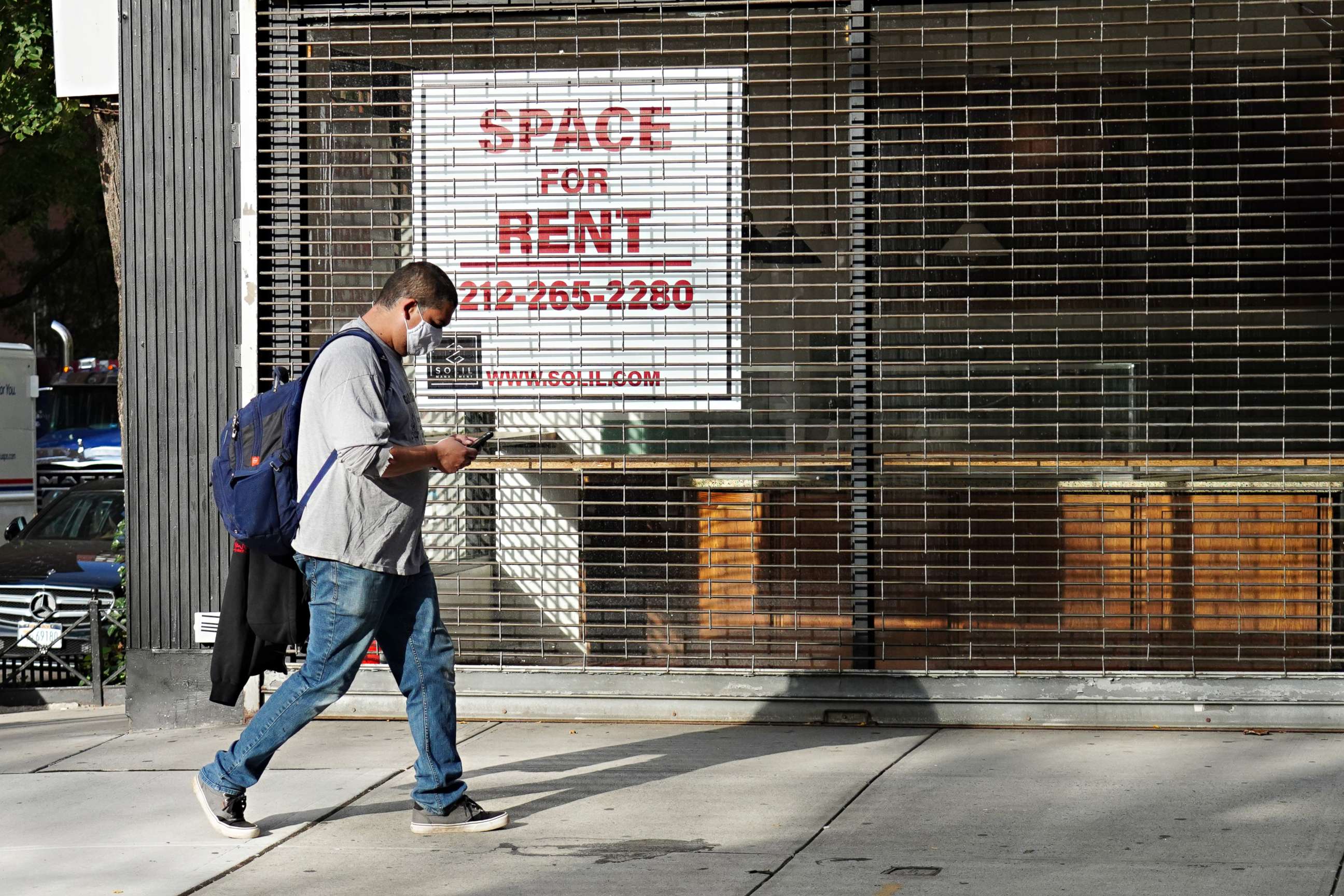PHOTO: A man wearing a protective mask walks by a closed cafe with a sign in the window reading "SPACE FOR RENT" as the city continues reopening efforts following restrictions imposed to slow the spread of coronavirus on Oct. 19, 2020, in New York City.