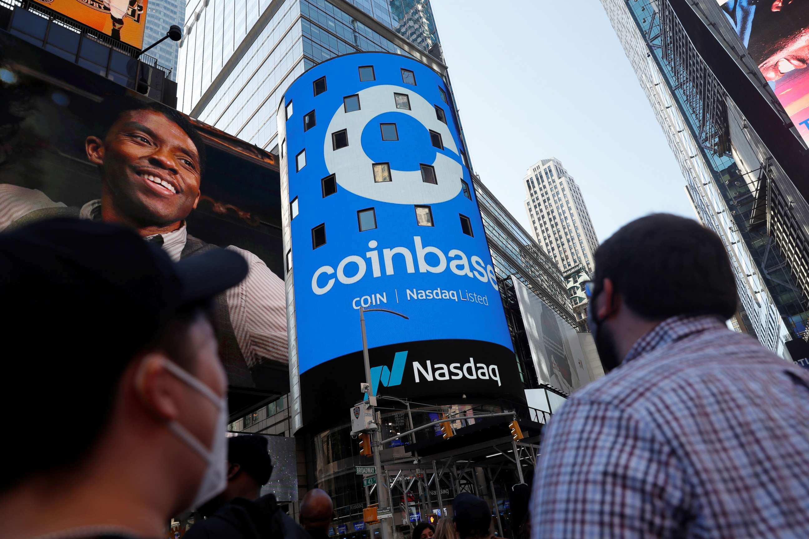 PHOTO: People watch as the logo for Coinbase Global Inc, the biggest cryptocurrency exchange, is displayed on the Nasdaq MarketSite jumbotron at Times Square in New York, April 14, 2021.