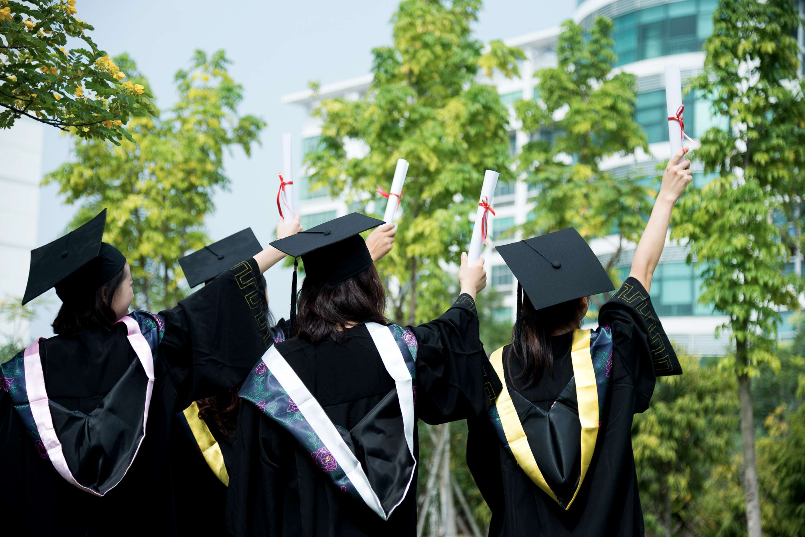 PHOTO: A rear view of female graduates wearing graduation caps and gowns at campus is captured in this undated stock photo.