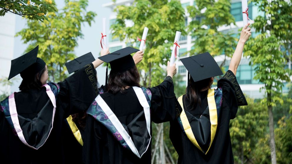 PHOTO: A rear view of female graduates wearing graduation caps and gowns at campus is captured in this undated stock photo.