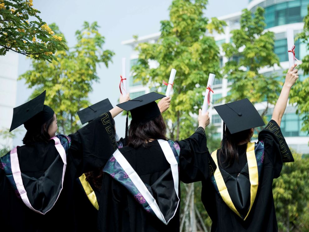 PHOTO: A rear view of female graduates wearing graduation caps and gowns at campus is captured in this undated stock photo.