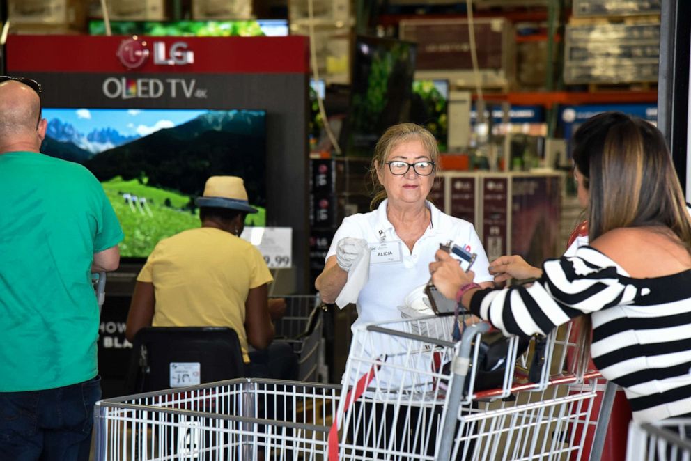PHOTO: A woman hands out disinfectant wipes for customers entering a North Miami Costco store amid concern over the COVID-19 virus, March 120, 2020.
