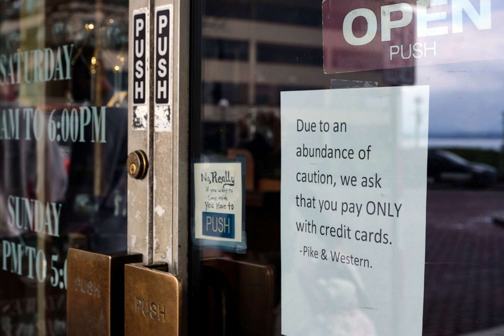 PHOTO: A sign posted on a door at a store near Pike Place Market, an area tourist attraction, requests credit card payments only, March 11, 2020, in Seattle.