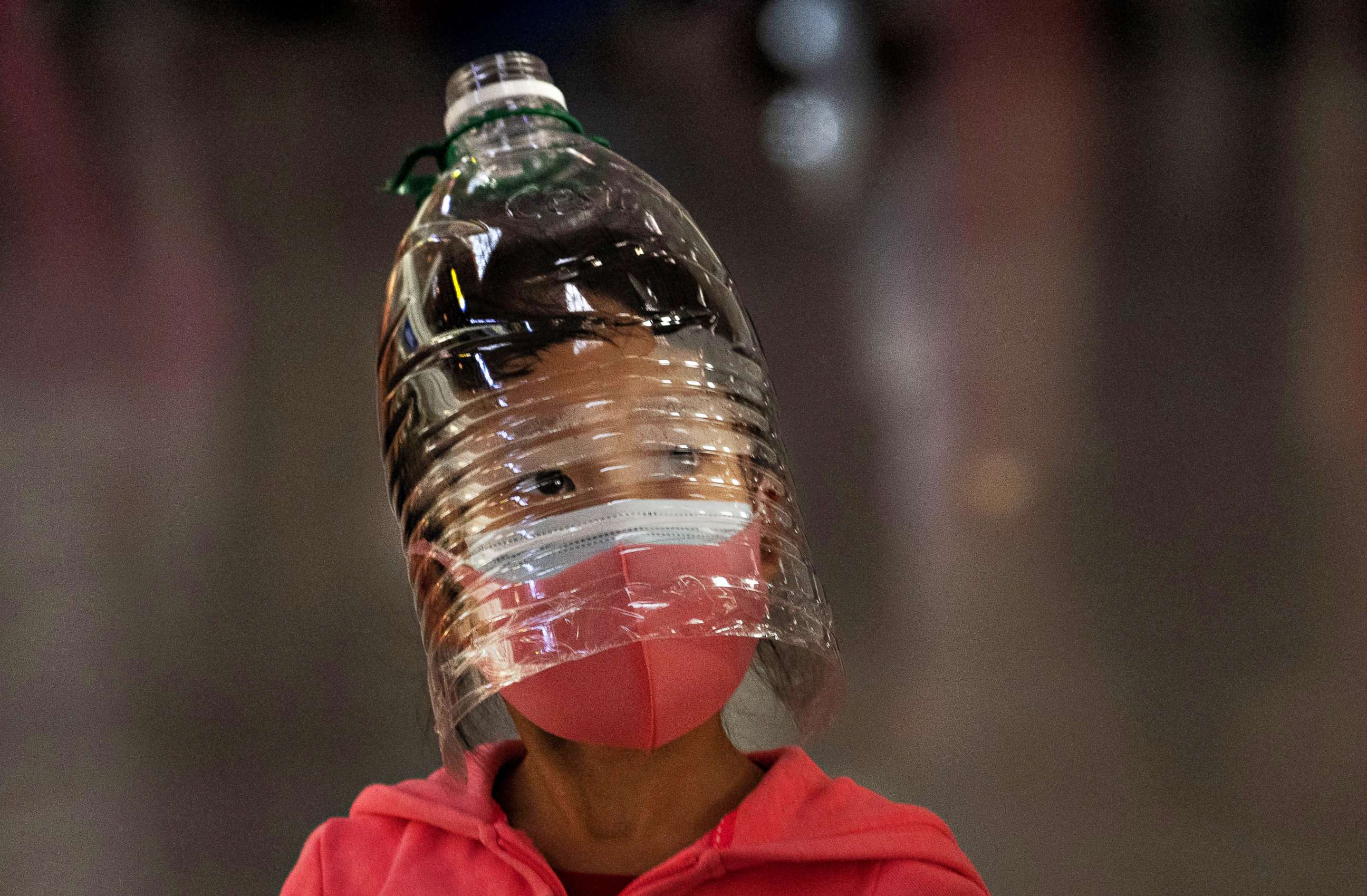 PHOTO: A girl wears a plastic bottle as a makeshift protection and a face mask while waiting to check in for a flight at Beijing Capital Airport on Jan. 30, 2020 in China.