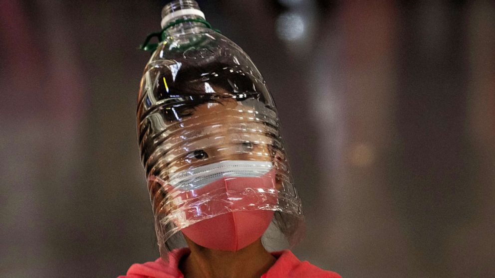 PHOTO: A girl wears a plastic bottle as a makeshift protection and a face mask while waiting to check in for a flight at Beijing Capital Airport on Jan. 30, 2020 in China.