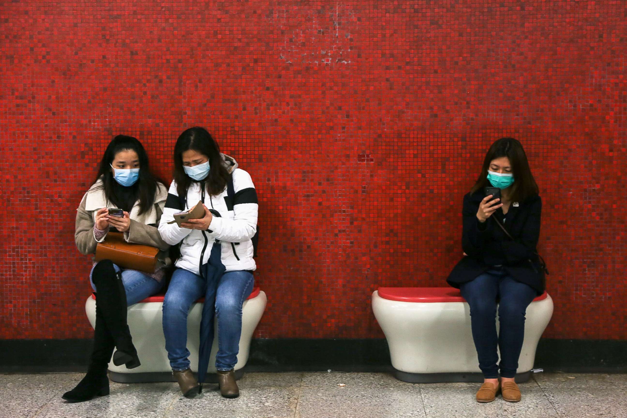 PHOTO: Passengers wearing face masks look at their mobile phones while waiting for the subway in Hong Kong, Jan. 26, 2020, during the Coronovirus outbreak.