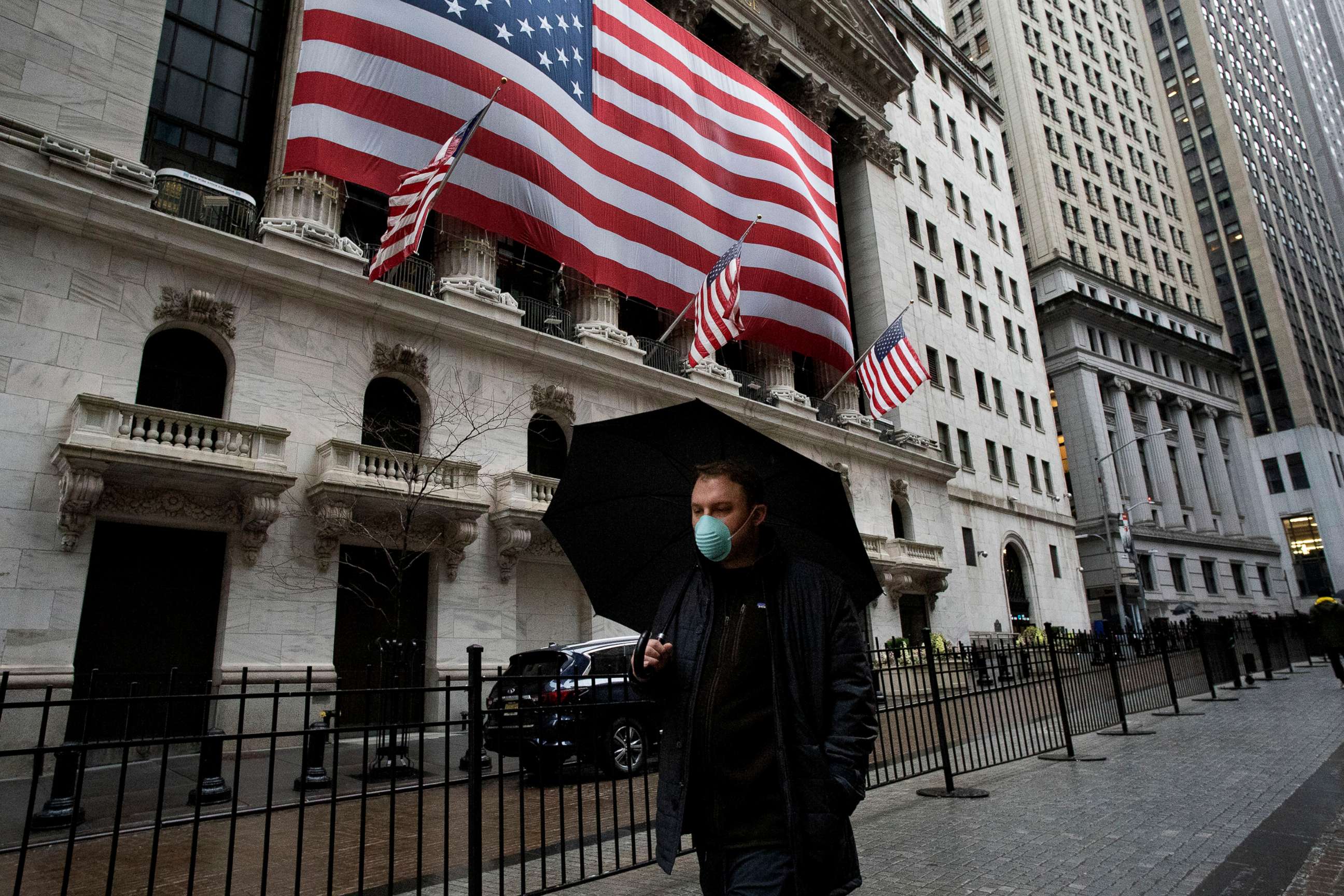 PHOTO: A man wearing a mask walks by the New York Stock Exchange, March 17, 2020. 