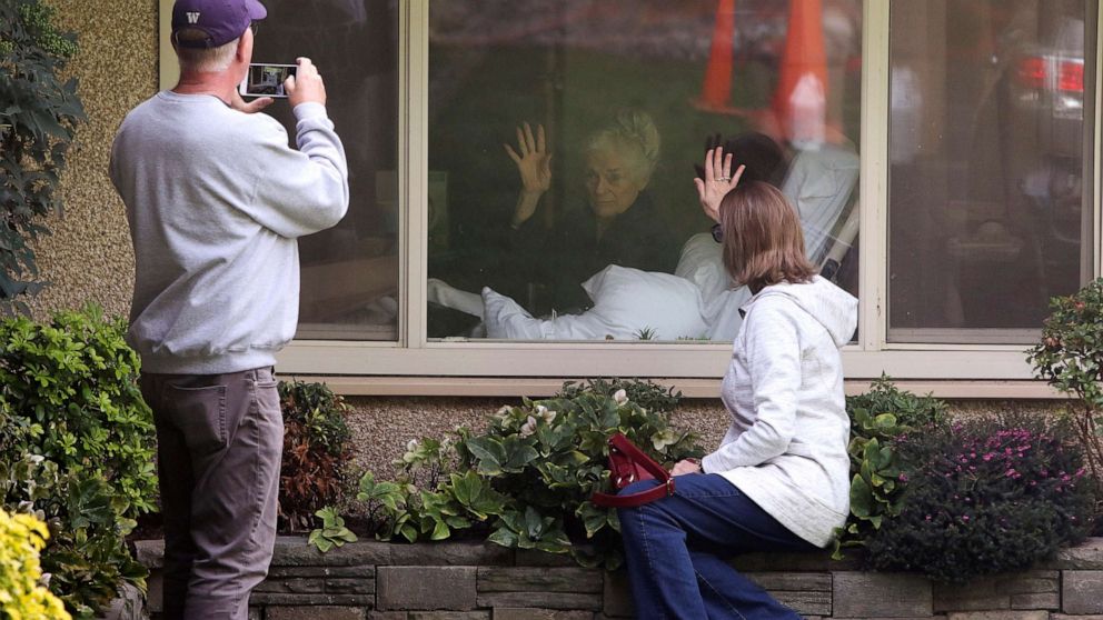 PHOTO: Lori Spencer and husband Michael Spencer visit outside the room of Lori's mom Judie Shape, 81, who Lori says has tested positive for coronavirus, at Life Care Center in Kirkland, Wash., March 11, 2020. 