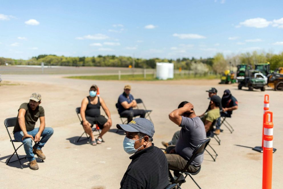 PHOTO: Farm workers wait outside a mobile COVID-19 vaccine clinic at a fruit and vegetable farm in Foley, Minn., on May 12, 2021.