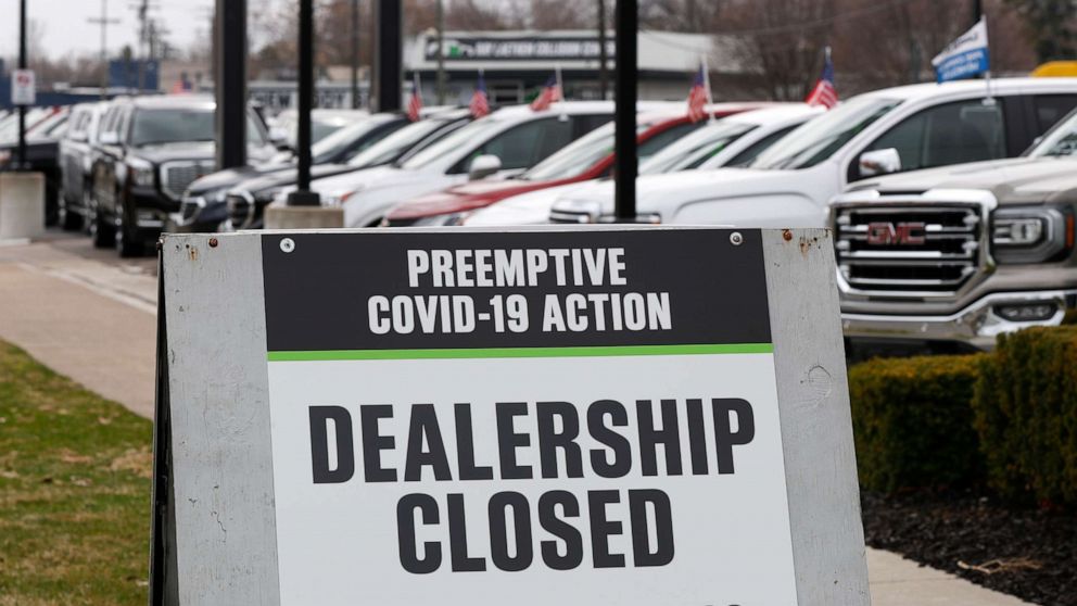 PHOTO: A sign showing an automobile dealership closed as a preemptive COVID-19 action, March 26, 2020 in Detroit. 