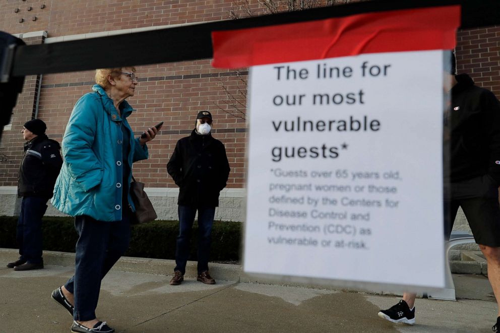 PHOTO: Shoppers wait to enter at a Target store in Glenview, Ill., March 25, 2020. 