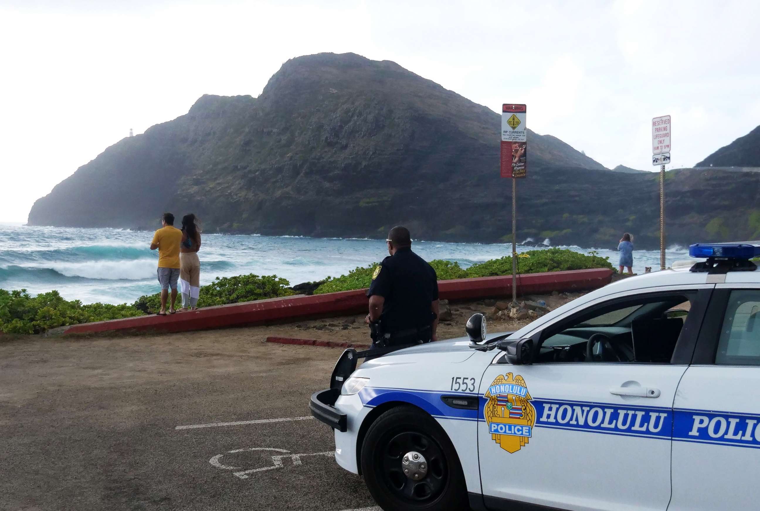 PHOTO: Police wait for people to return to their cars before closing the beach parking lot in preparation for Hurricane Douglas, in Honolulu, on July 26, 2020. 