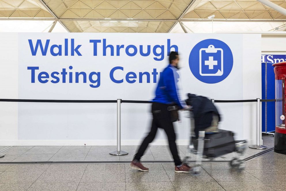 PHOTO: A passenger passes a sign for a Walk Through Coronavirus Testing Centre at London Stansted Airport, on Jan. 10, 2022.