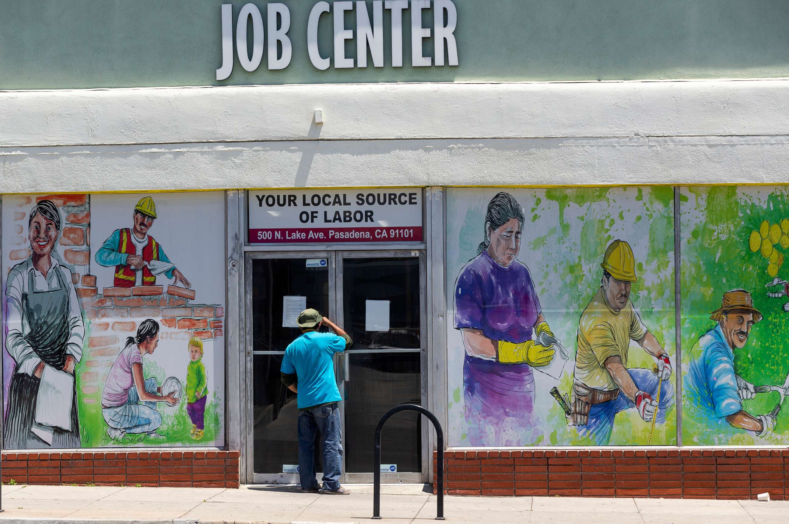 PHOTO: A person looks inside the closed doors of the Pasadena Community Job Center in Pasadena, Calif., May 7,2020.