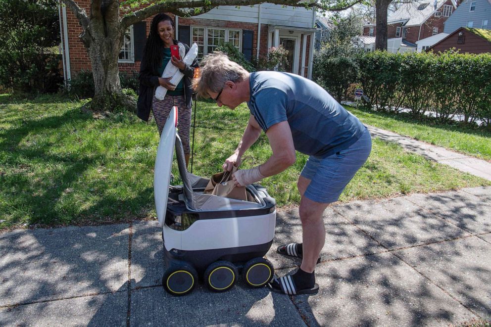 PHOTO: A man unloads a food delivery robot from the Broad Branch Market grocery store in Washington, DC., on April 9, 2020. 