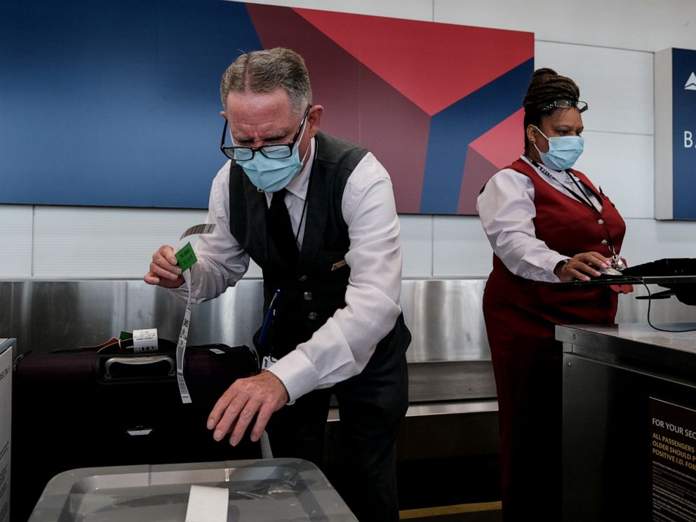 PHOTO: Delta Airline employees check in luggage at the Ronald Reagan National Airport, July 22, 2020, in Arlington, Virginia.