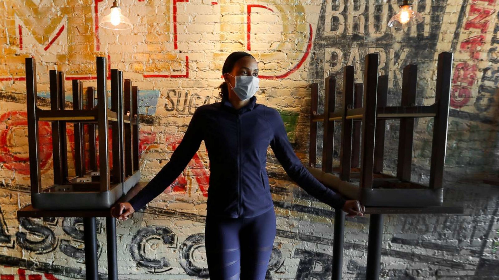 PHOTO: In this Thursday, May 21, 2020, image, Stephanie Byrd, co-owner of The Block, poses for a photo with chairs on the tables while the restaurant is closed due to the coronavirus in Detroit.