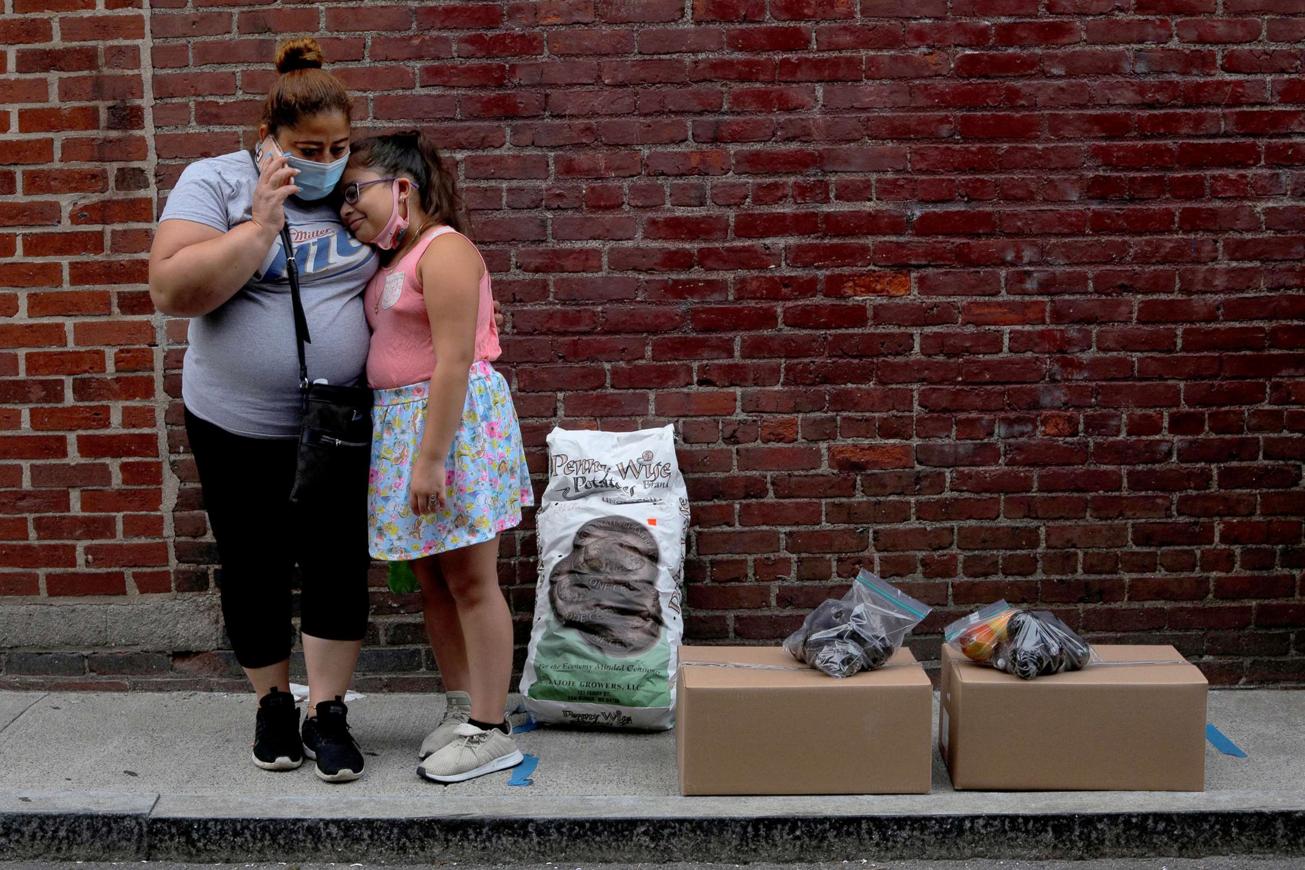 PHOTO: Sandra Cruz, who lost her job because of the COVID-19 pandemic and fell behind on her rent, waits for a ride with her daughter after picking up free groceries distributed a social services agency in Chelsea, Mass., July 22, 2020.