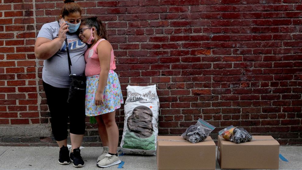 PHOTO: Sandra Cruz, who lost her job because of the COVID-19 pandemic and fell behind on her rent, waits for a ride with her daughter after picking up free groceries distributed a social services agency in Chelsea, Mass., July 22, 2020.